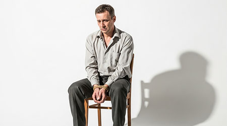 Мужчина средних лет сидит с завязанными руками